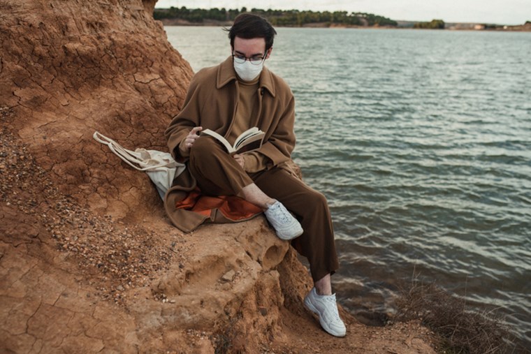 MAN READING A BOOK BY THE SEA